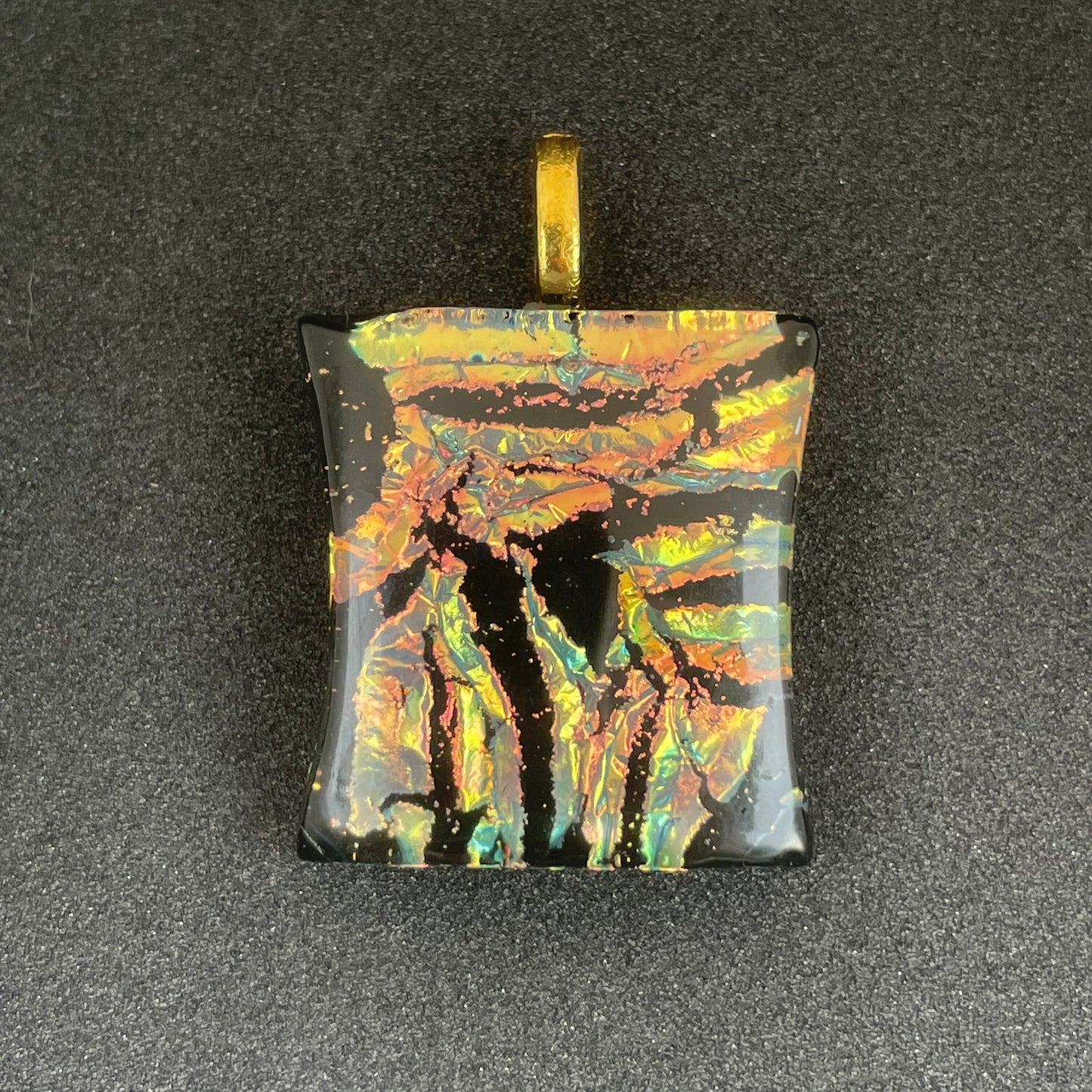 Gold, peach and hints of teal on black dichroic glass pendant with leather cord.